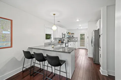 a kitchen with stainless steel appliances a dining table chairs and wooden floor