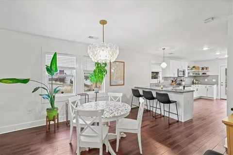 a view of a dining room and livingroom with furniture wooden floor a chandelier