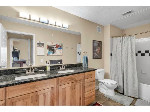 a bathroom with a granite countertop sink a toilet a mirror and shower