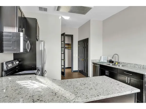 a living room with stainless steel appliances kitchen island granite countertop a refrigerator and a sink