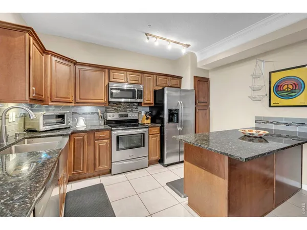 a kitchen with stainless steel appliances granite countertop a stove top oven a refrigerator a sink and dishwasher