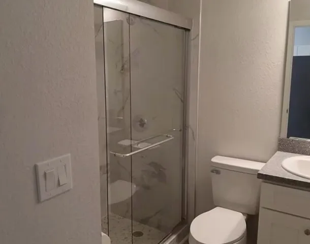 a white toilet sitting next to a shower