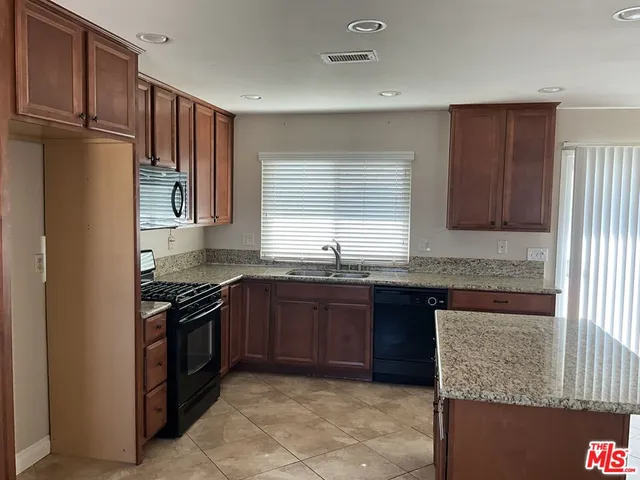 a kitchen with stainless steel appliances granite countertop wooden cabinets a stove top oven and granite counter tops