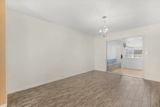 an empty room with wooden floor cabinet and windows