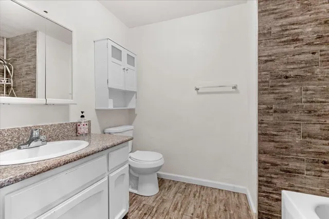 a bathroom with a granite countertop sink a toilet and a mirror