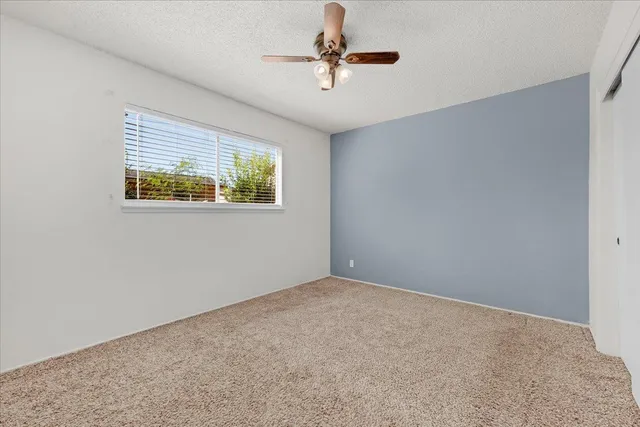 an empty room with windows and fan