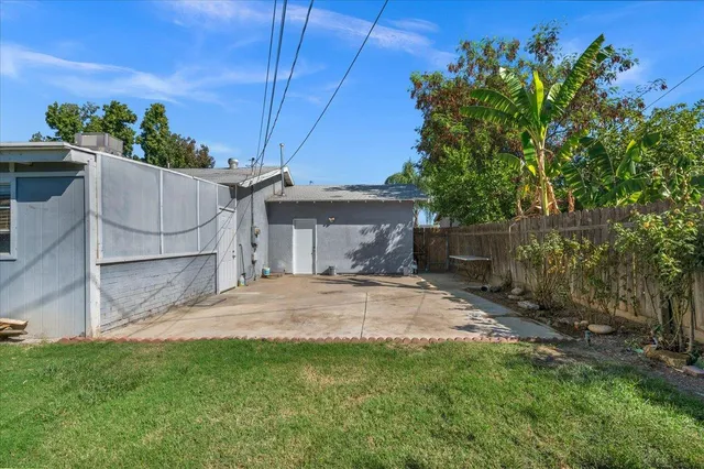 a white house with a small yard and wooden fence
