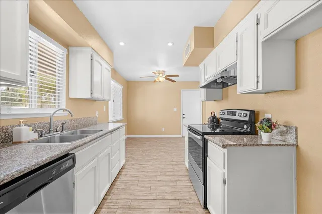 a kitchen with stainless steel appliances granite countertop a sink stove and cabinets