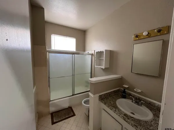 a bathroom with a granite countertop sink toilet and mirror