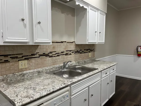 a kitchen with granite countertop a sink a stove and cabinets