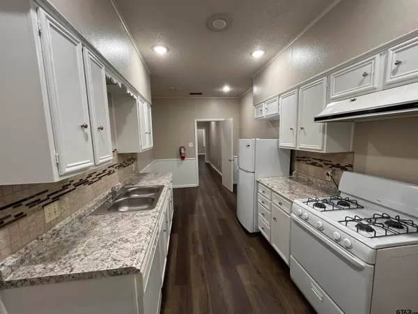 a kitchen with kitchen island granite countertop a sink stove and refrigerator