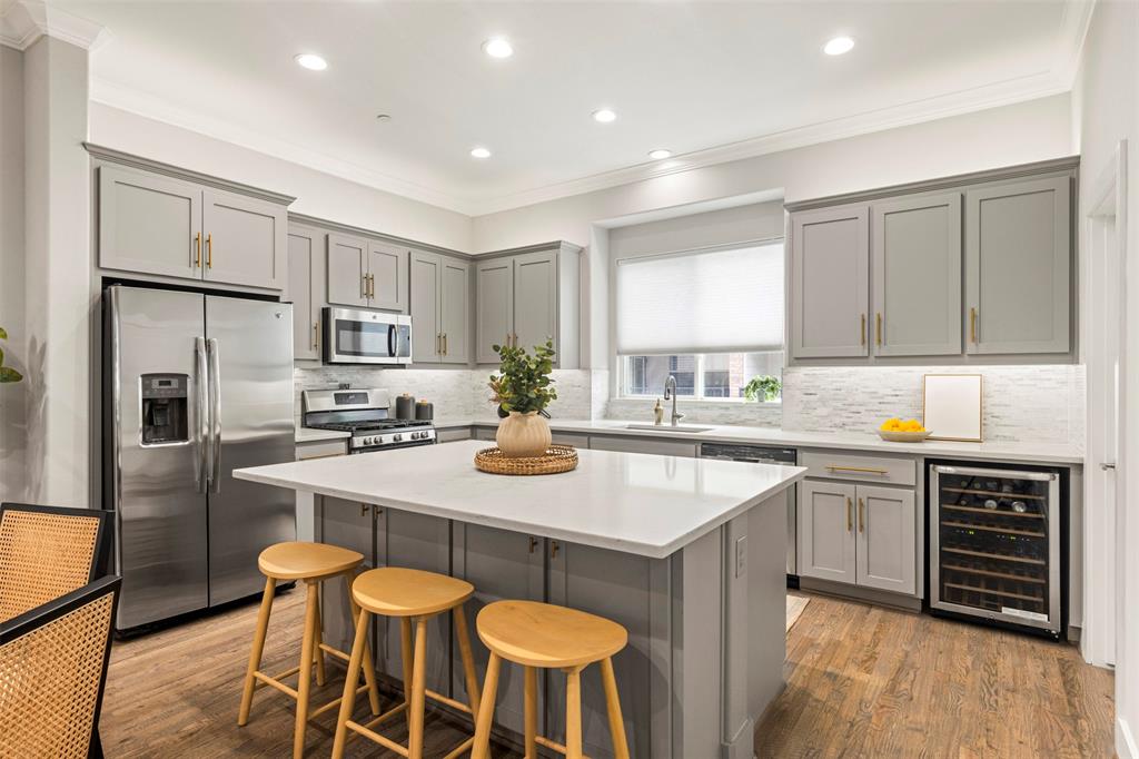 a kitchen with stainless steel appliances granite countertop a sink a stove a refrigerator cabinets and chairs