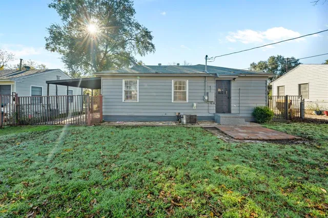 a backyard of a house with plants and large tree