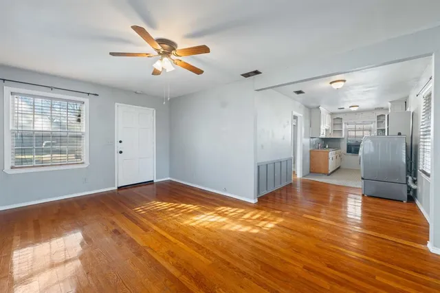 a view of an empty room with wooden floor and a window