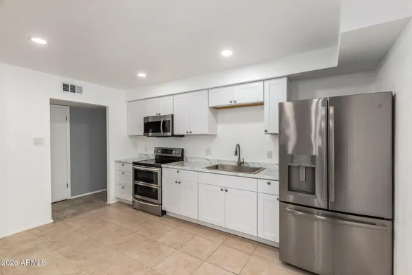 a kitchen with stainless steel appliances granite countertop a refrigerator and a stove top oven