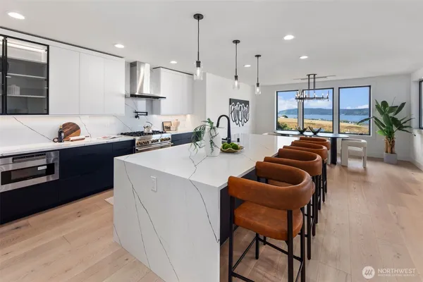 a kitchen with stainless steel appliances kitchen island granite countertop a stove a sink a refrigerator and chairs