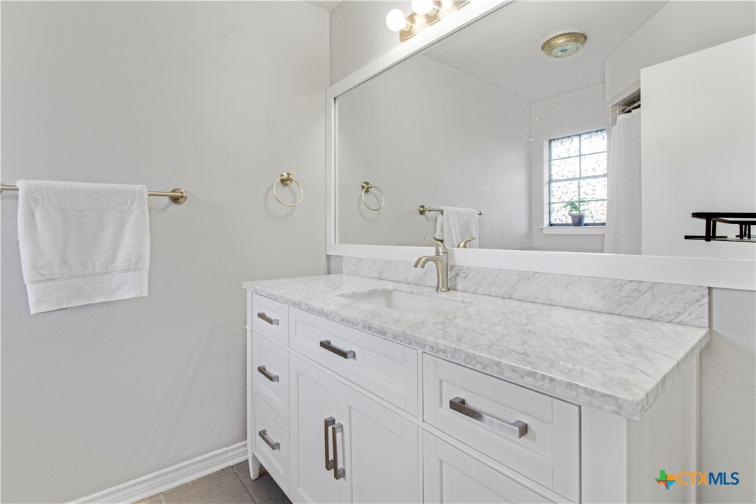 4314 Fox Trail Temple, TX 76504 - Photo 13 of 22 a bathroom with a granite countertop sink and white cabinets