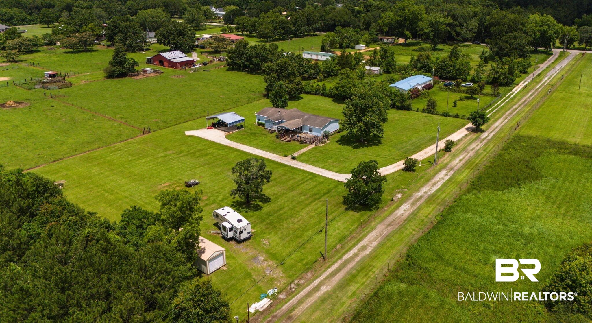 34985b Spring Road South, Unit B Stapleton, AL 36578 - Photo 27 of 31 Expansive property featuring a light blue residence with a covered carport, multiple outbuildings, and extensive green space