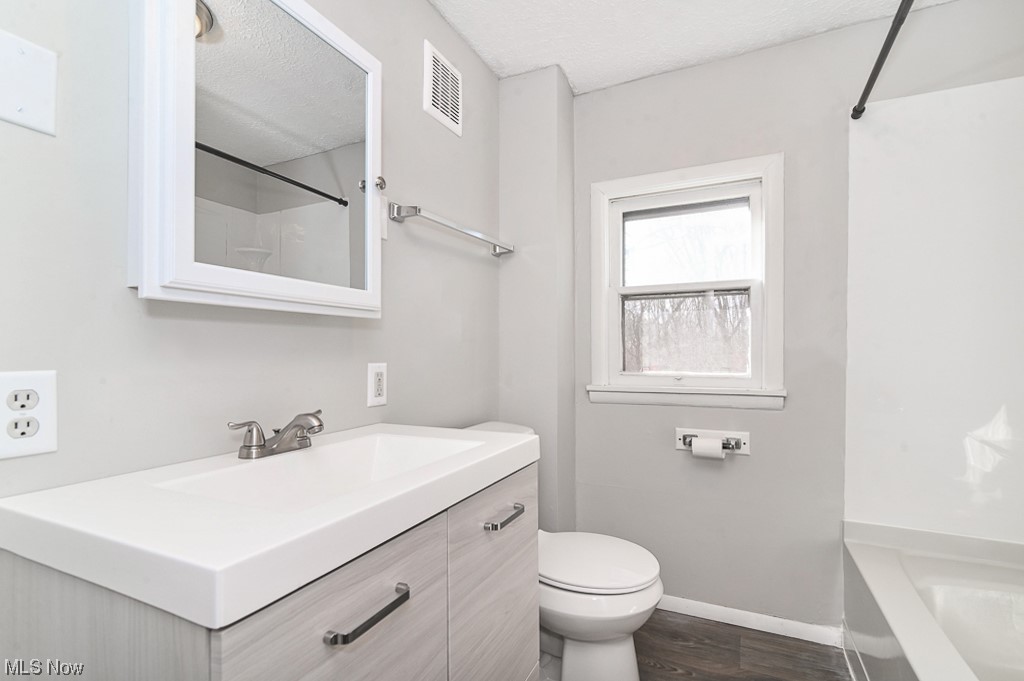 6469 Red Brush Road Ravenna, OH 44266 - Photo 22 of 34 Full bathroom featuring toilet, a textured ceiling, shower / bath combination, hardwood / wood-style flooring, and vanity