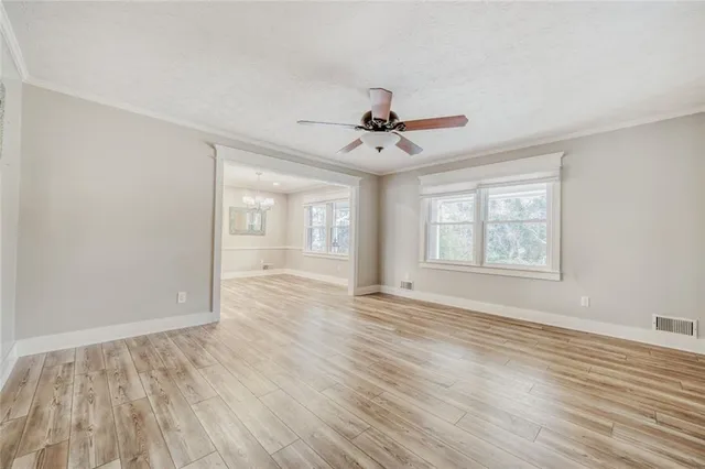 a view of an empty room with window and wooden floor