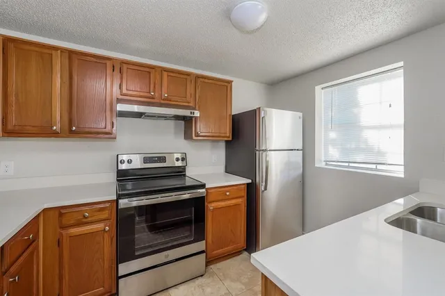 a kitchen with stainless steel appliances granite countertop a refrigerator stove and sink