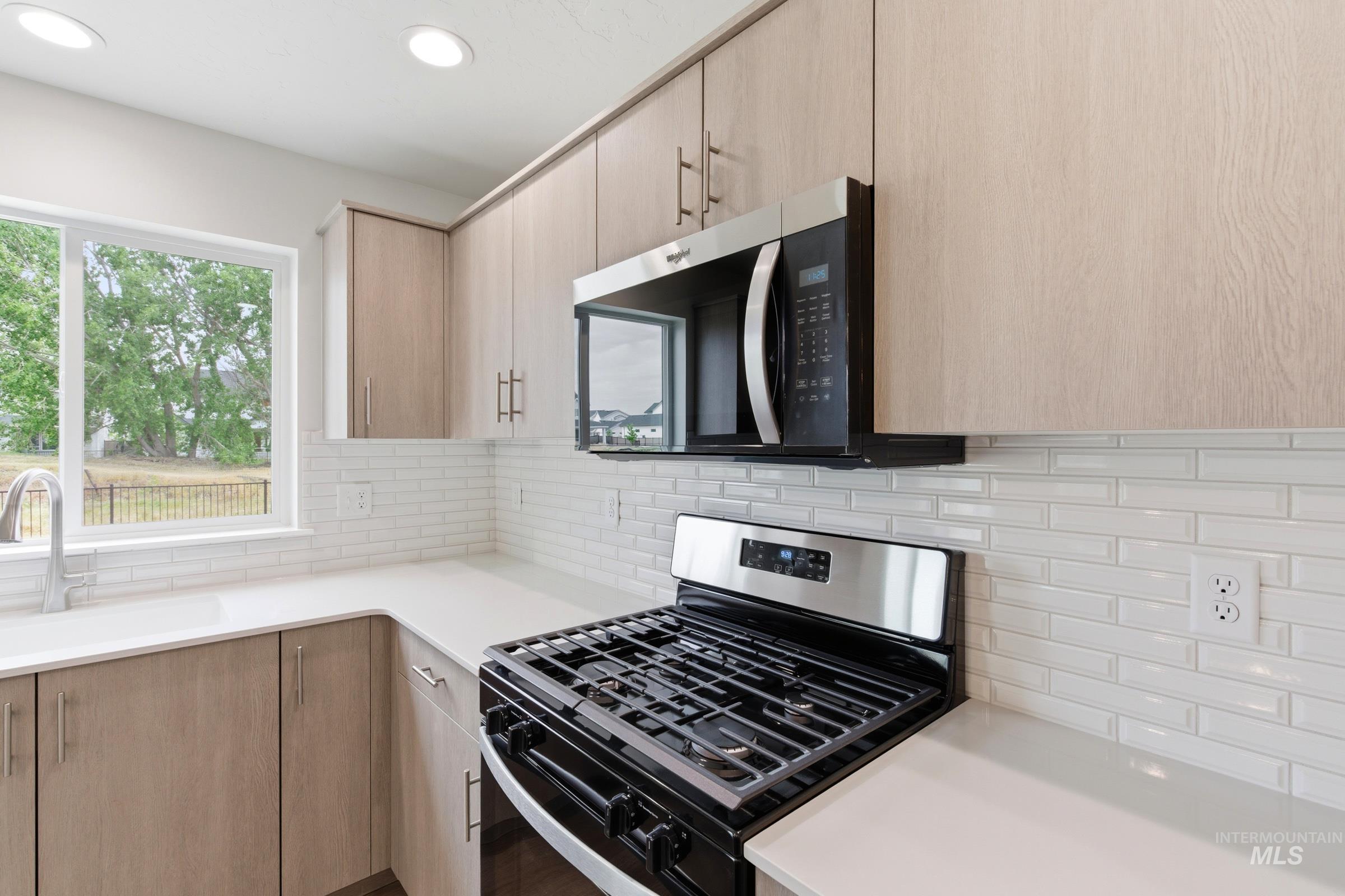 12829 Decatur Street Nampa, ID 83651 - Photo 4 of 33 Modern kitchen featuring light wood-finish cabinetry, white countertops, and a white subway tile backsplash