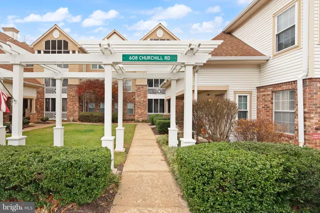 a view of a brick house with a yard plants and large tree