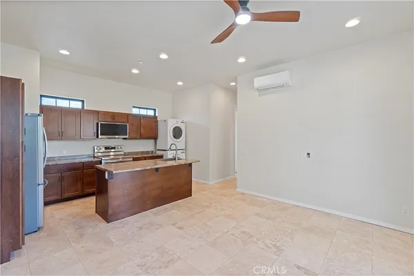 a large kitchen with stainless steel appliances a large counter top a stove a chimney a sink and a refrigerator