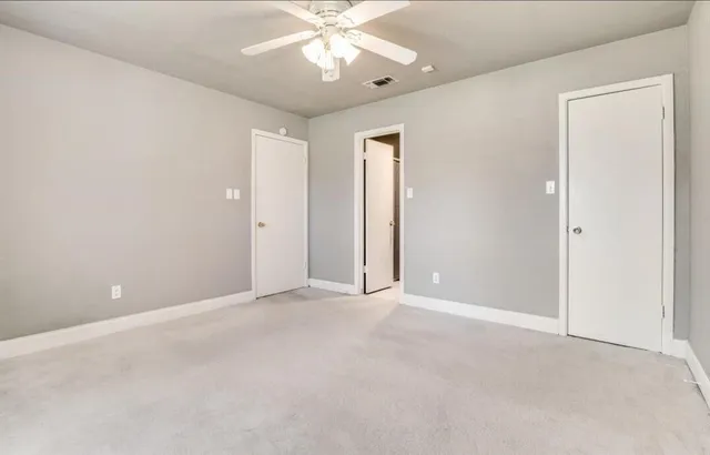 an empty room with a chandelier fan and windows