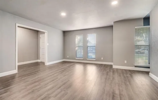 a view of an empty room with wooden floor and a window