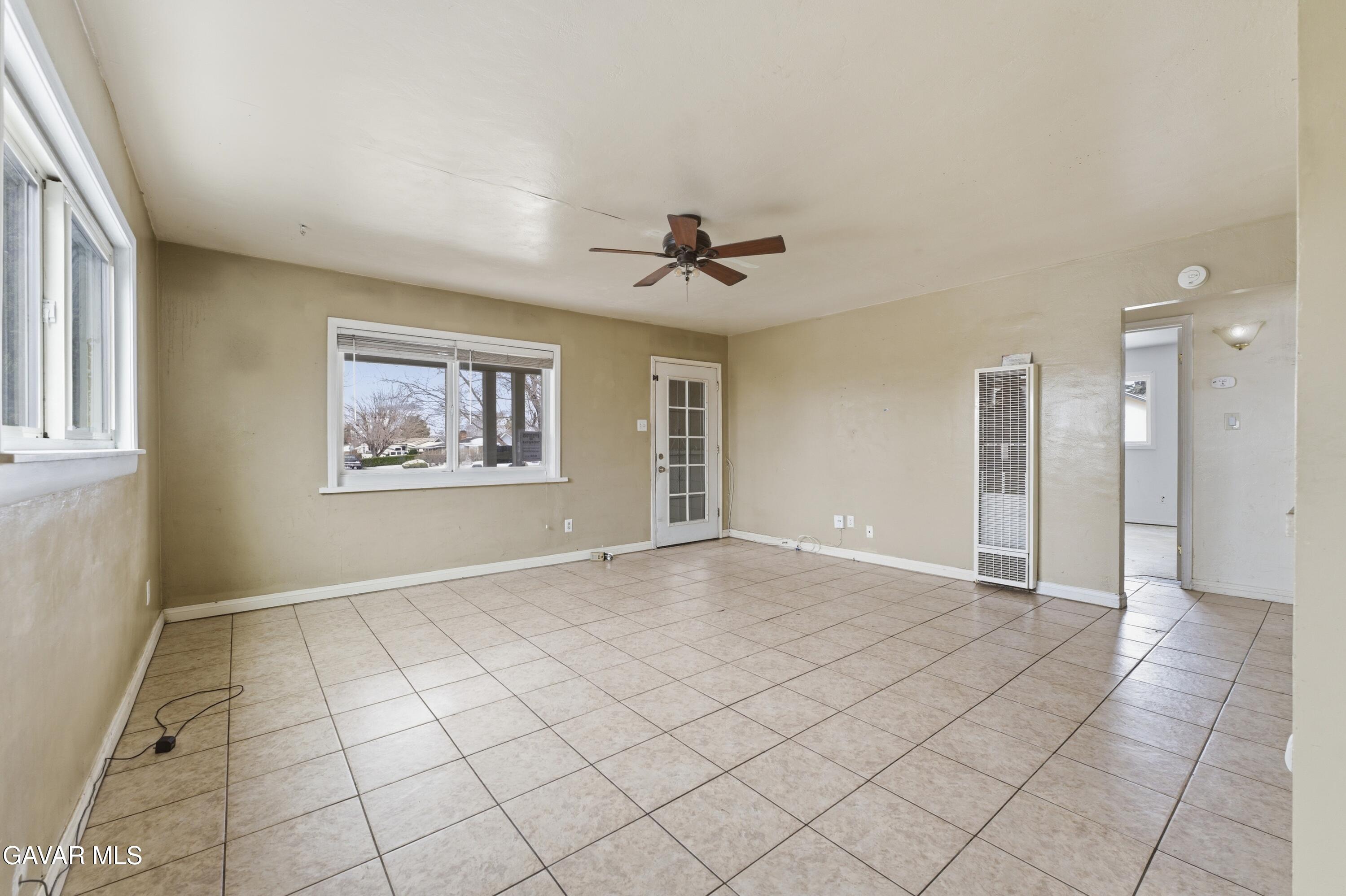 an empty room with a ceiling fan and window