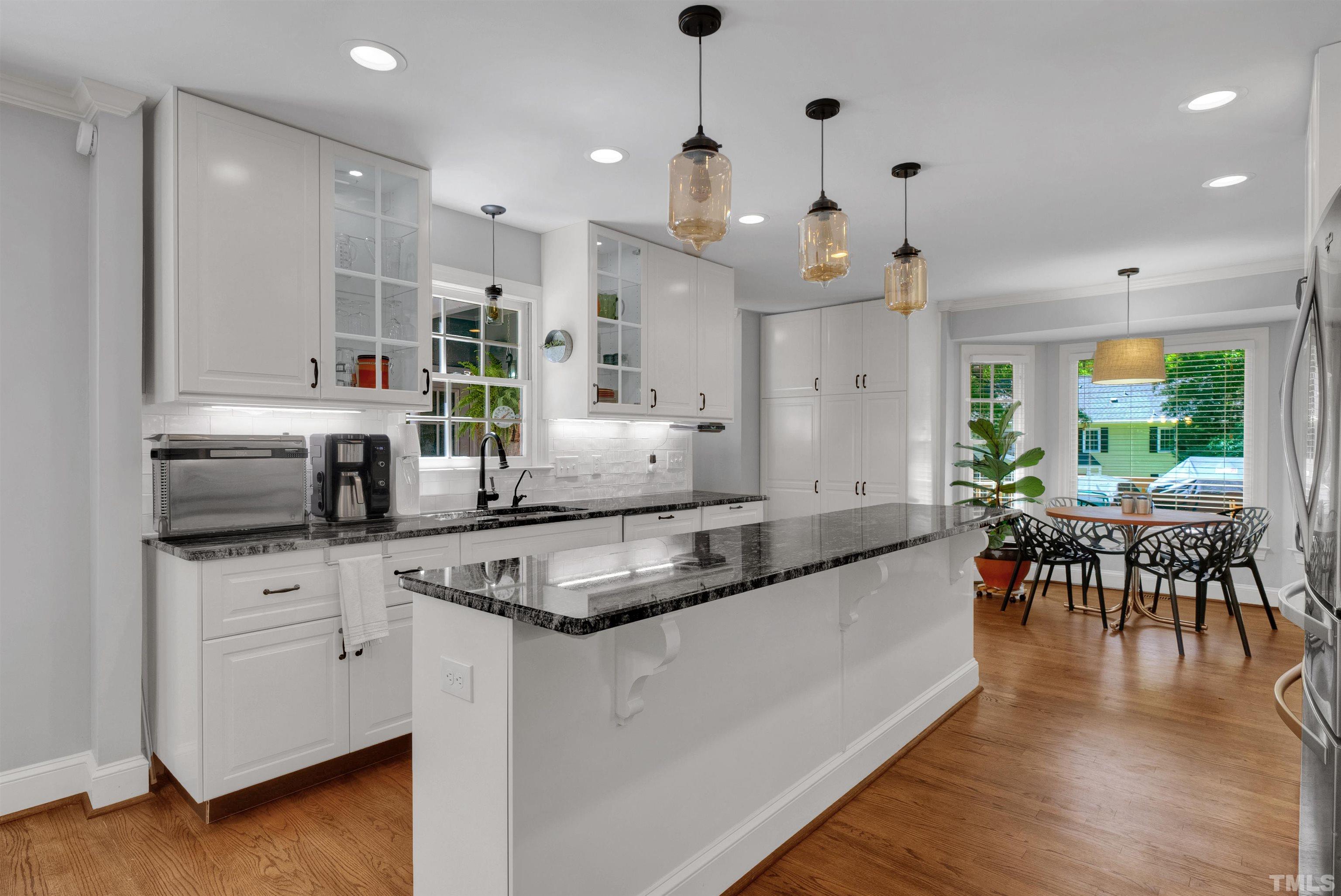 8209 Blue Heron Way Raleigh, NC 27615 - Photo 15 of 31 a large kitchen with stainless steel appliances kitchen island granite countertop a stove a sink a dining table and chairs with wooden floor