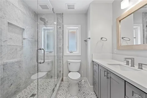 a bathroom with a toilet sink vanity granite and shower