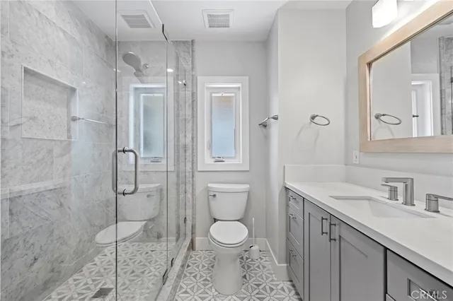 a bathroom with a toilet sink vanity granite and shower