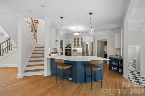a kitchen with stainless steel appliances kitchen island granite countertop a table chairs and a wooden floor