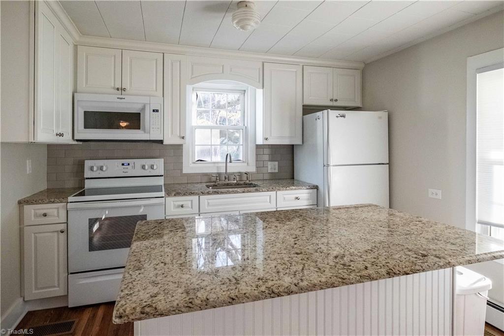 663 Ruritan Road Roaring River, NC 28669 - Photo 18 of 43 Kitchen features eat-in island, newer cabinetry and granite countertops with subway tile backsplash.