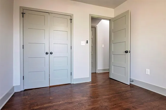 an empty room with wooden floor & closet area
