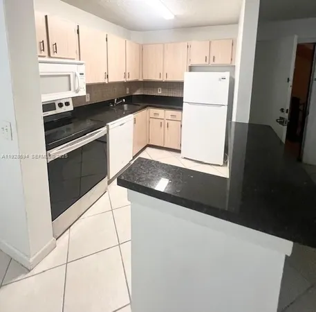 a kitchen with granite countertop white cabinets and white appliances