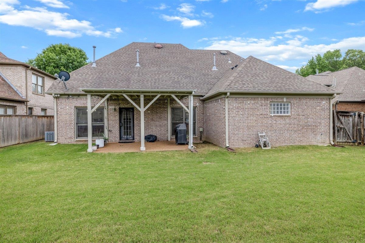 744 Southern Home Road Collierville, TN 38017 - Photo 18 of 24 Expansive grassy backyard featuring a covered patio with white support beams, brick exterior, and a shingle roof
