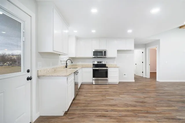 a large kitchen with granite countertop a sink and stainless steel appliances