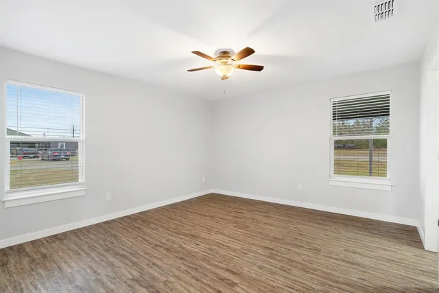 a view of an empty room with wooden floor and a window