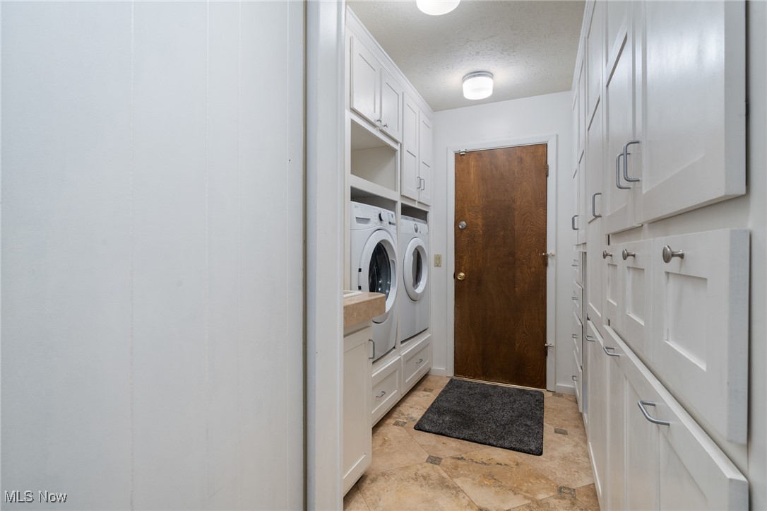 17800 Falling Leaves Road Strongsville, OH 44136 - Photo 24 of 39 Clothes washing area with washing machine and clothes dryer, a textured ceiling, and cabinet space