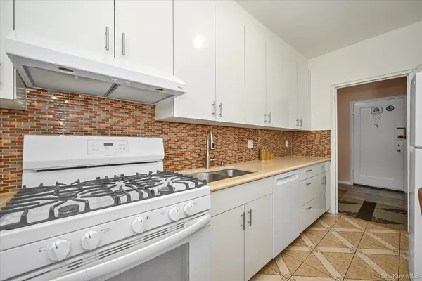 a kitchen with white cabinets and stove
