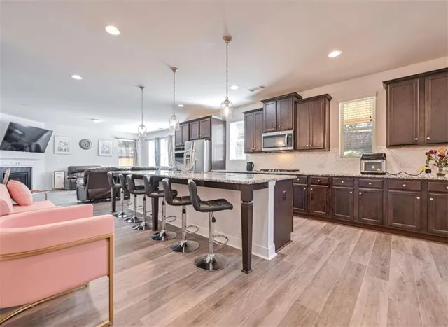a kitchen with stainless steel appliances kitchen island granite countertop wooden floors and view living room