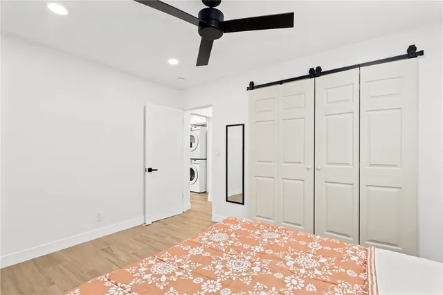 a view of an empty room with wooden floor and a ceiling fan