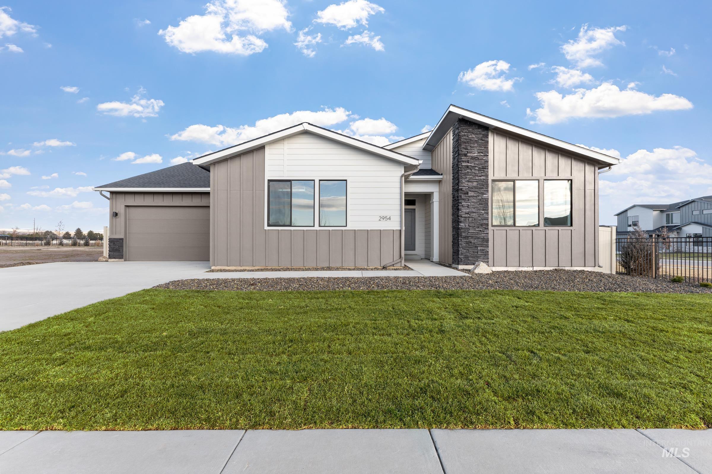 View of front of property with board and batten siding, stone siding, concrete driveway, and a garage