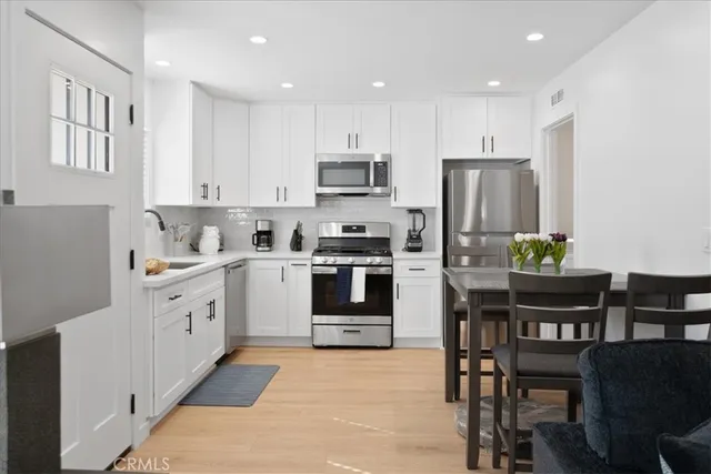 a kitchen with white cabinets and stainless steel appliances
