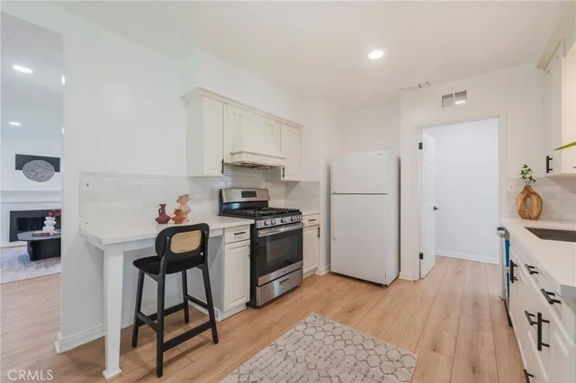 a kitchen with stainless steel appliances a stove a refrigerator and a dining table with wooden floor