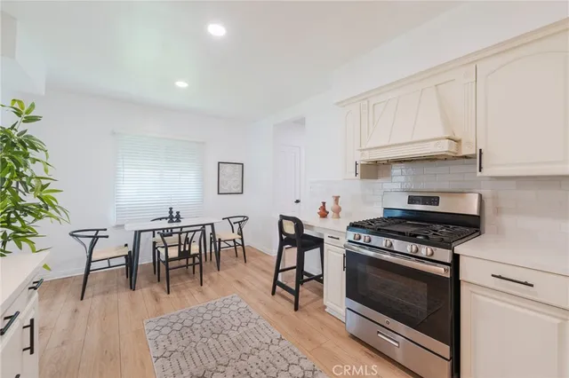 a kitchen with stainless steel appliances a stove a table and chairs in it