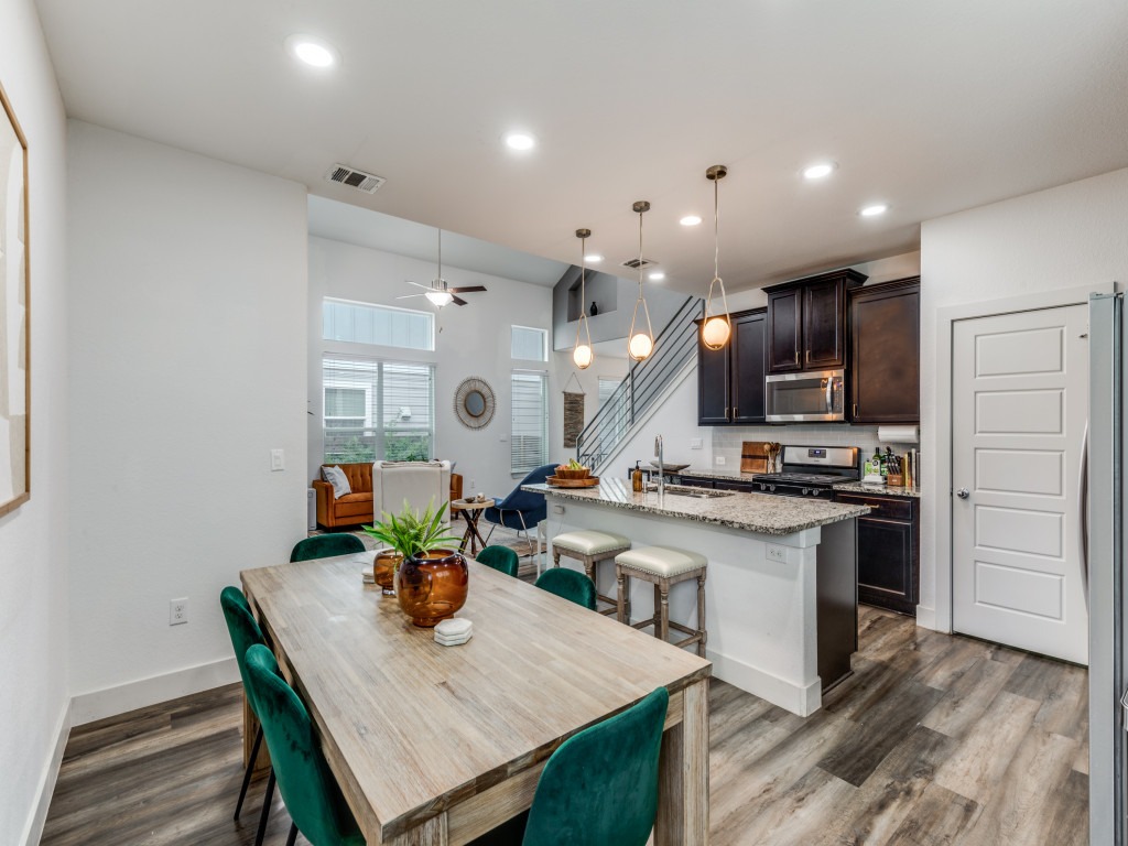 2204 Montague Street Austin, TX 78741 - Photo 11 of 25 a kitchen with stainless steel appliances granite countertop a stove refrigerator a sink dishwasher a dining table and chairs with wooden floor